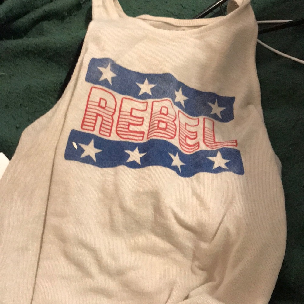 large tank top a cream color a banner with white stars and it says rebel